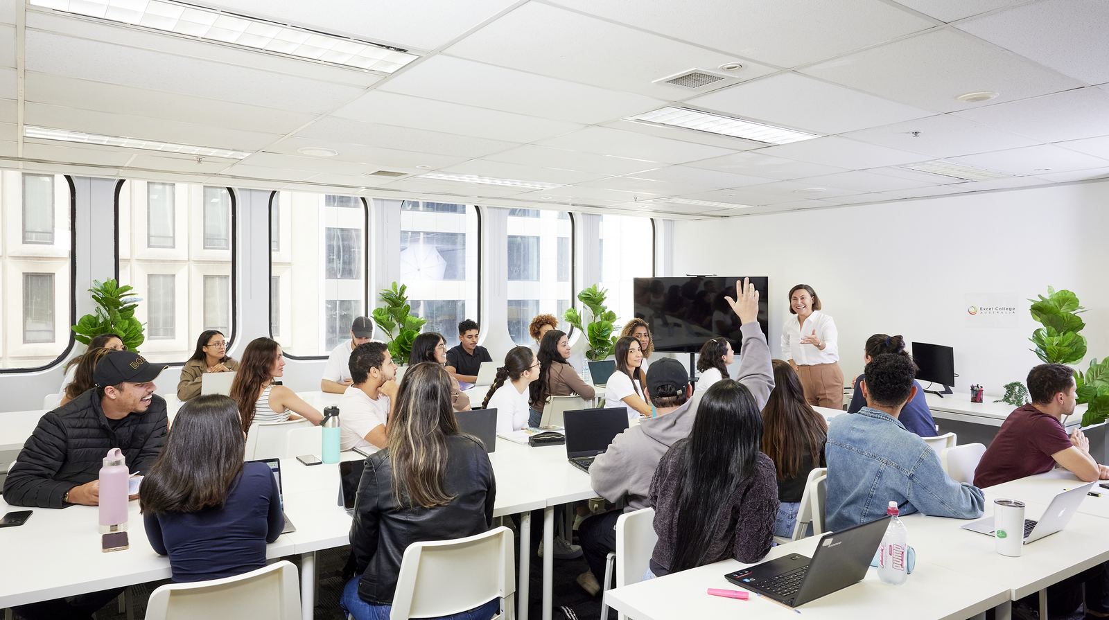 A full classroom of adult students during a Skills & Employment Australia training session, one student raising a hand