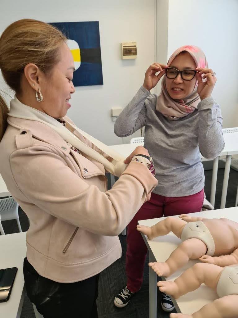 A trainee fitting an arm sling during a first aid training session