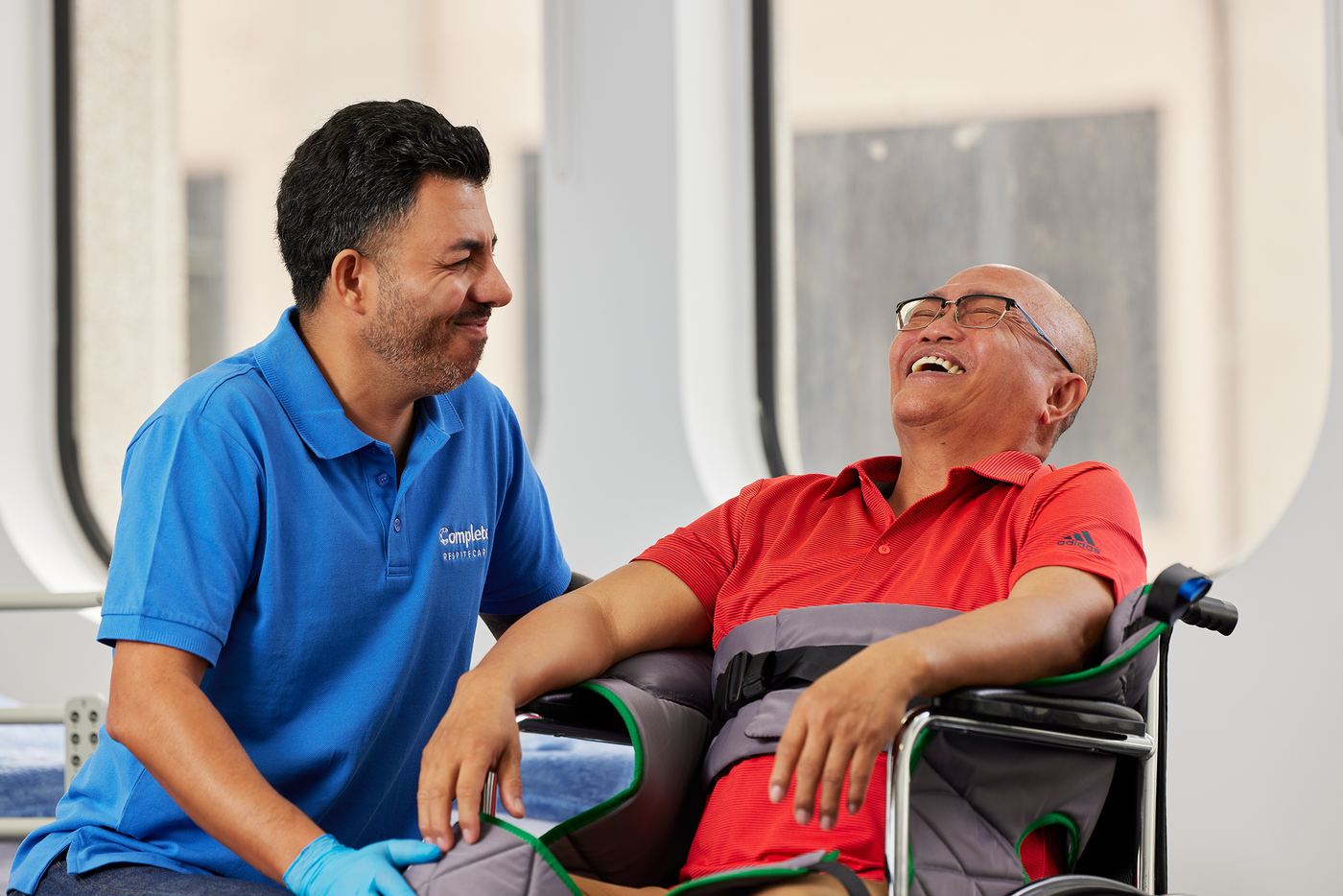 A carer and an older client laughing together in a bright care setting